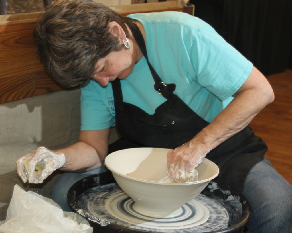A woman is working on a bowl in the process of making.
