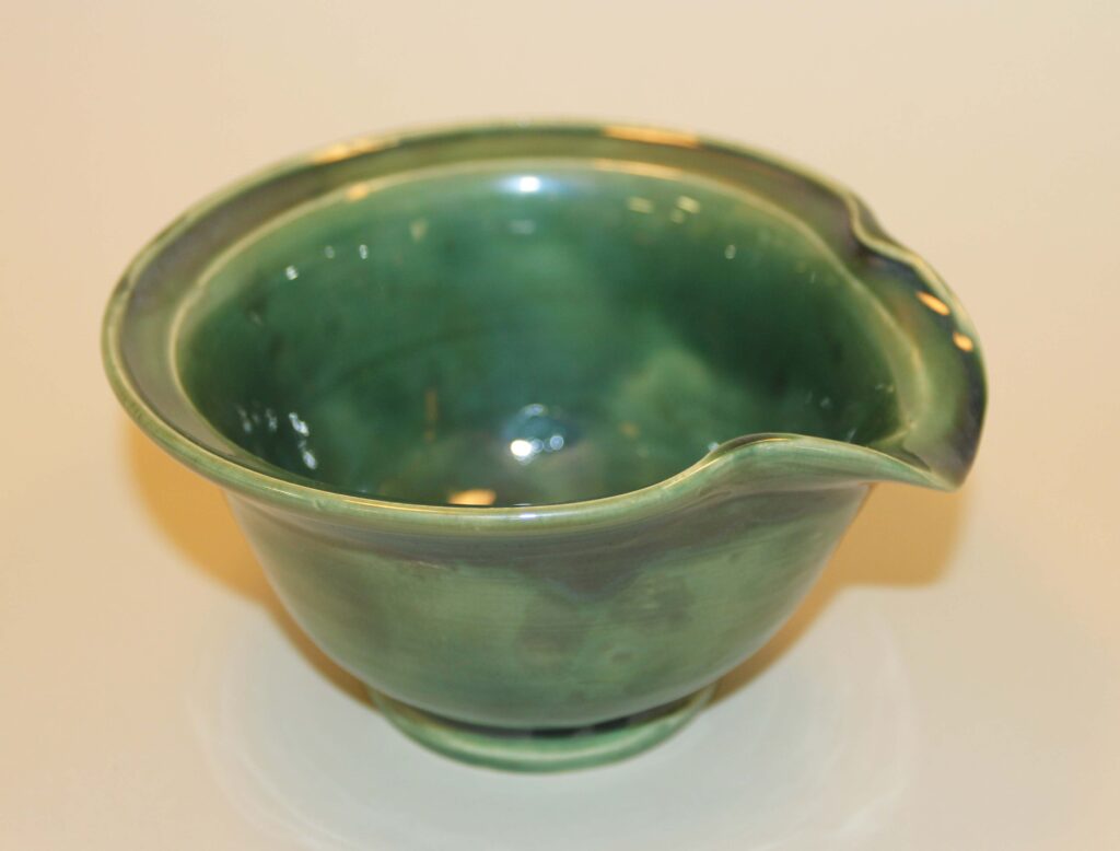A green bowl with a handle on the side.