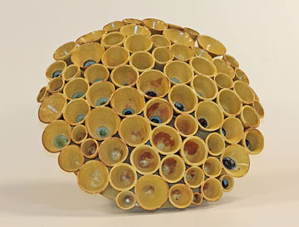 A yellow sculpture of tubes and pipes in the shape of a ball.