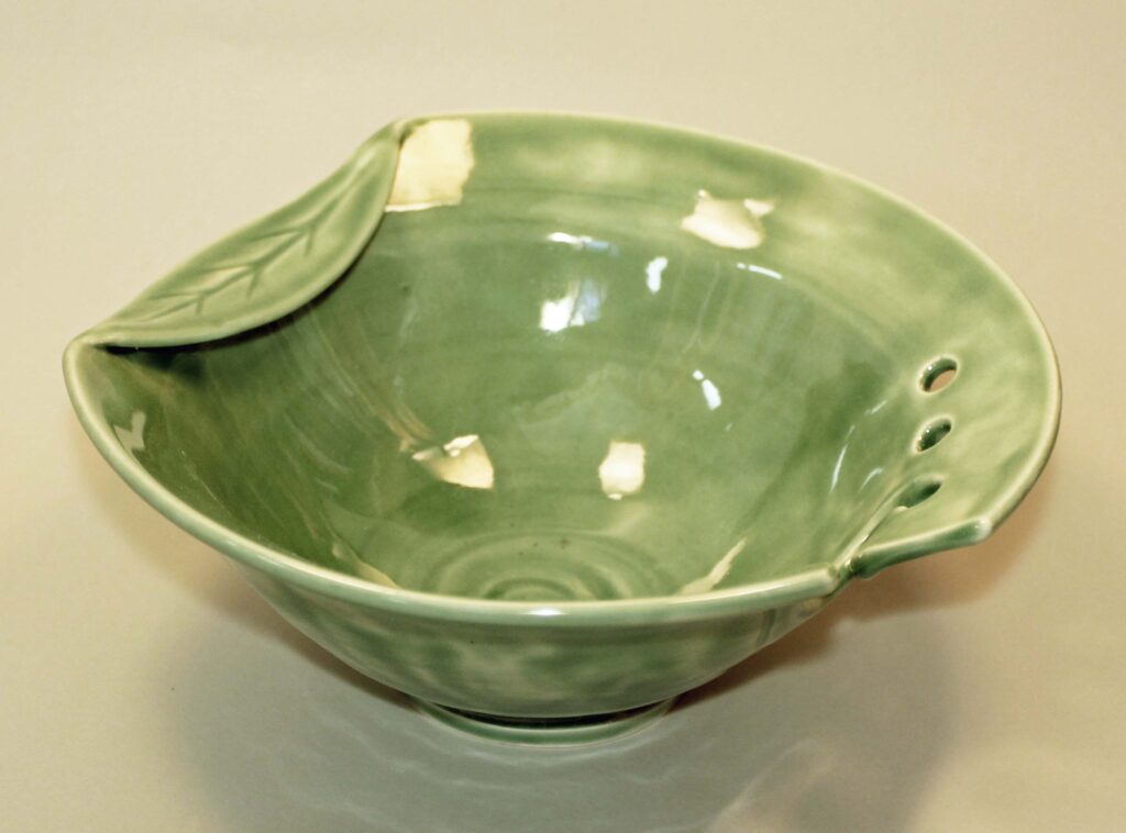 A green bowl with two holes on the side.
