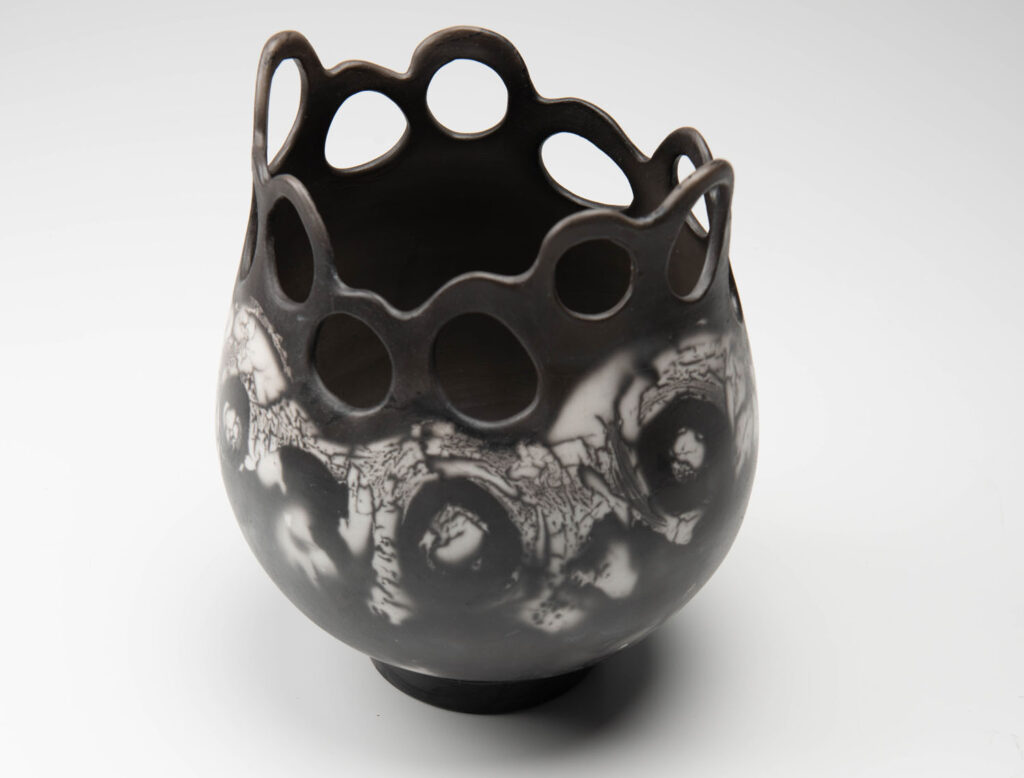 A black and white vase with holes in it
