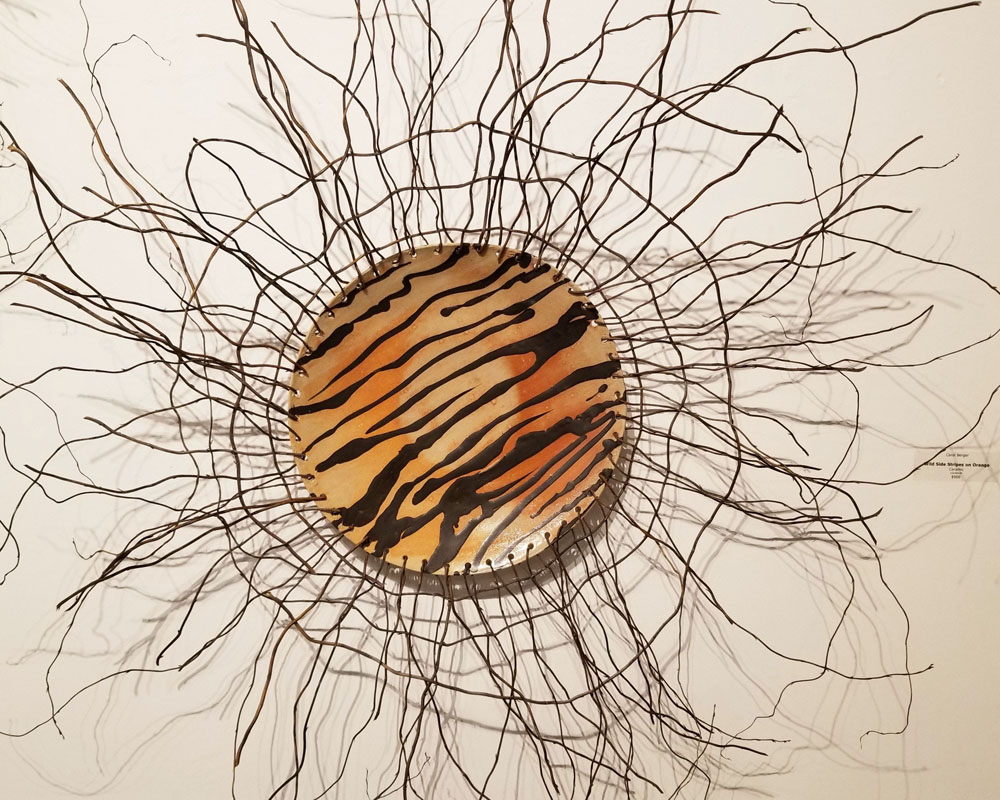 A circular sculpture of branches and tiger stripes.