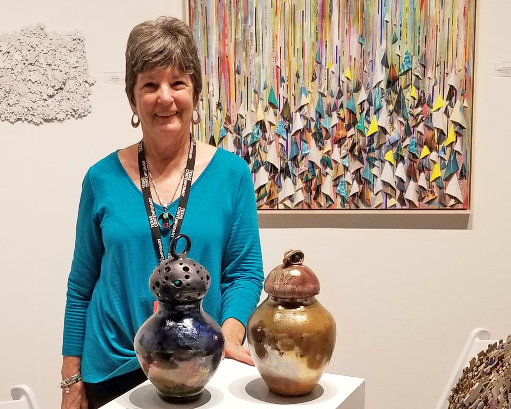 A woman standing next to two vases on a table.