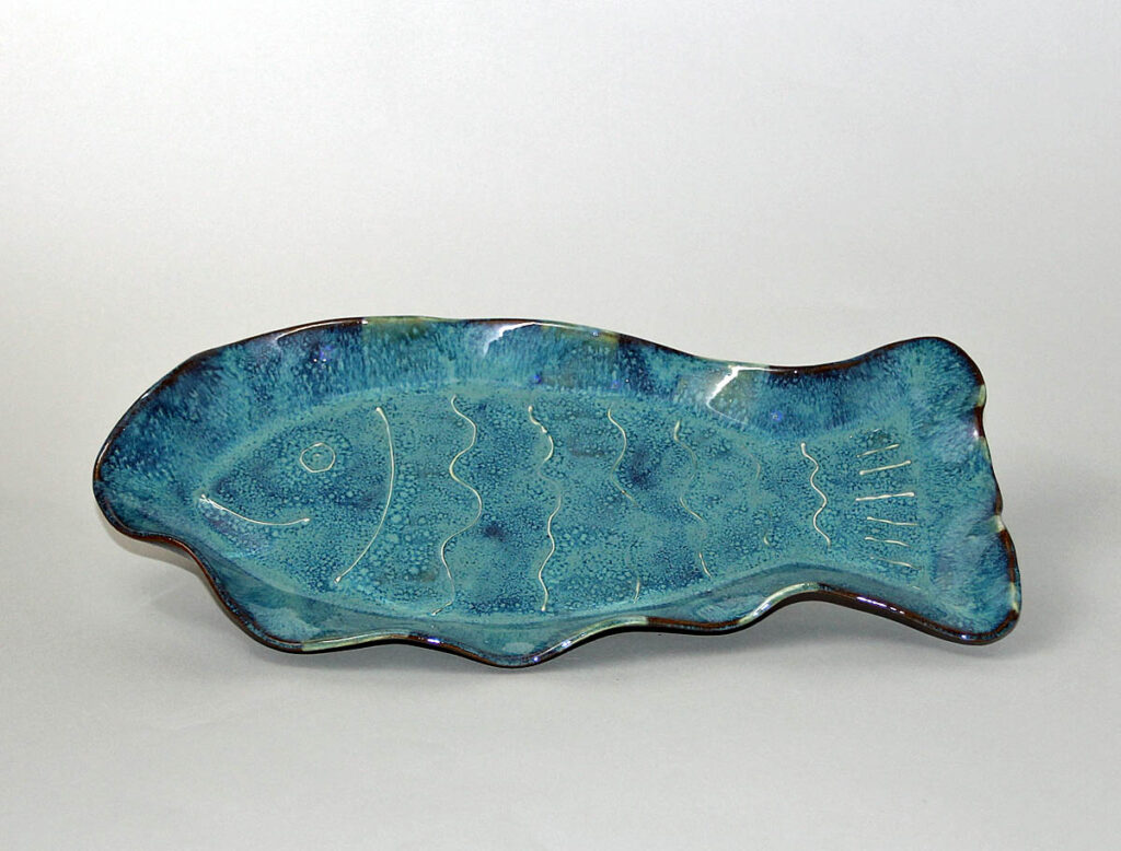 A blue fish shaped plate sitting on top of a table.
