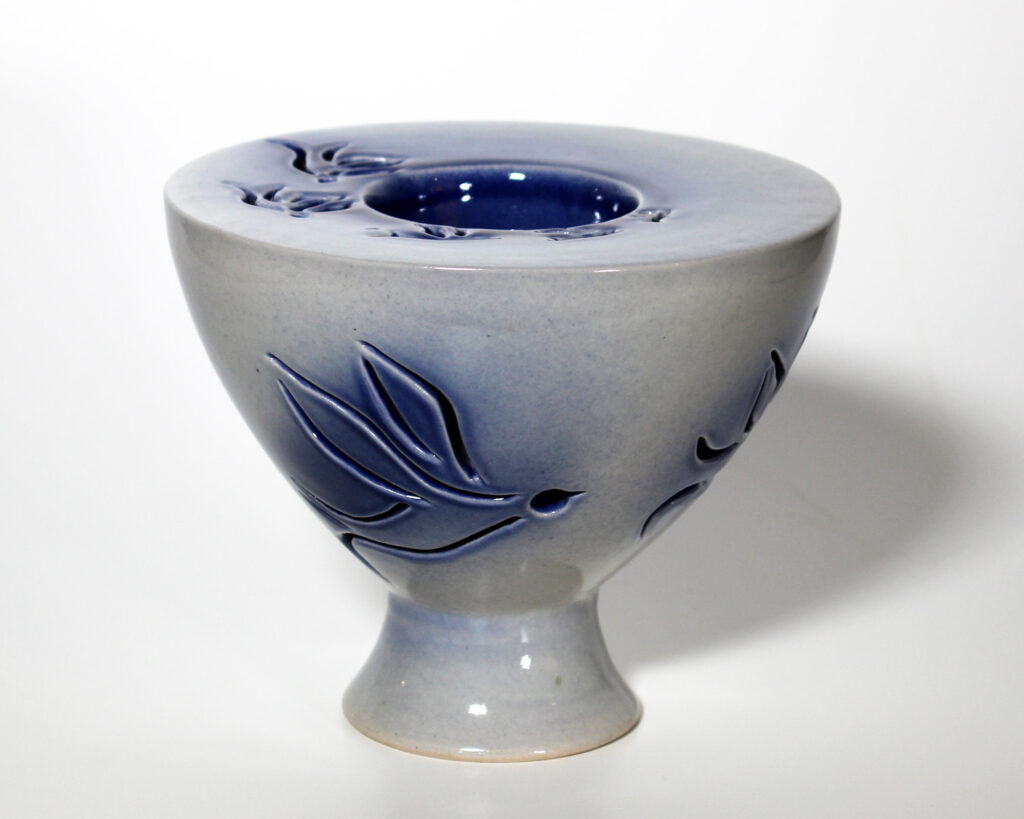 A blue and white vase with leaves on it