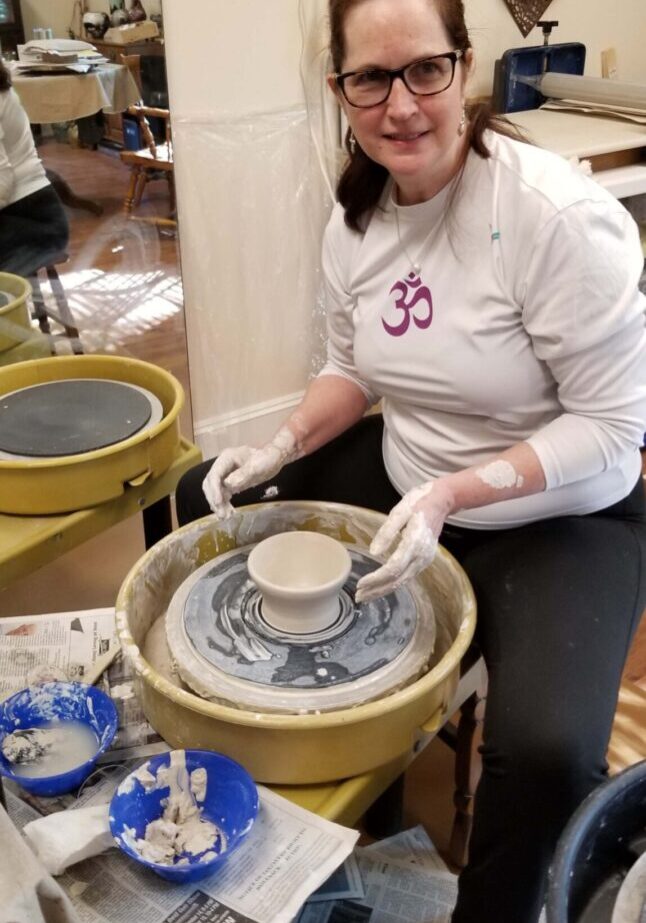 A woman is making pottery on the potter 's wheel.